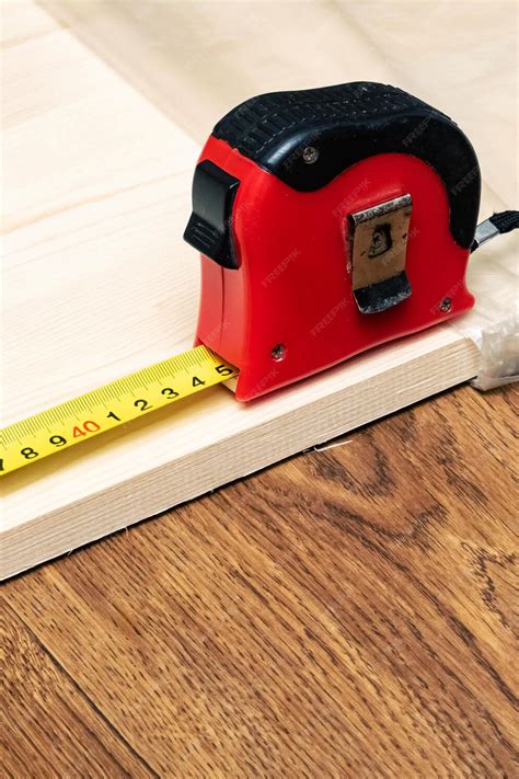 Premium Photo | Measuring a wooden board with a tape measure