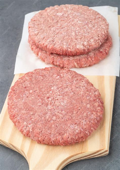 Premium Photo | Raw meat hamburger over wooden board