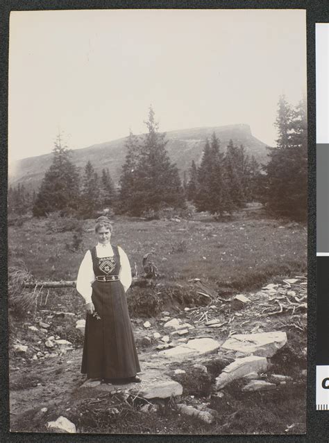 Photograph of a woman wearing a Norwegian folk costume standing by a