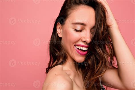 Studio shot of attractive laughing girl with wavy brown hair with nude
