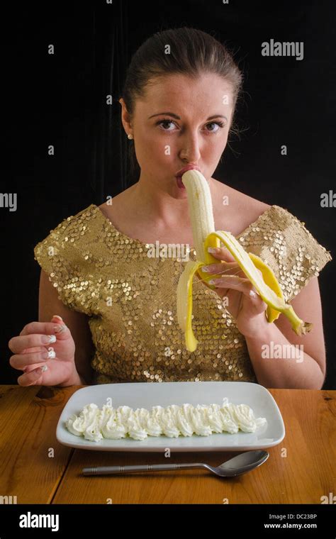 Smiling young woman eating a banana provocatively with squirty cream on a plate Stock Photo - Alamy