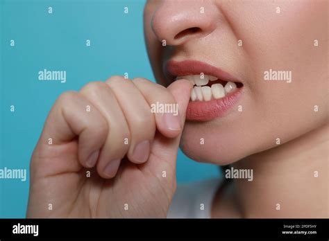 Young woman biting her nails on light blue background, closeup Stock ...