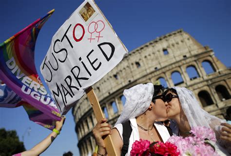 A lesbian couple kiss in front of the Colosseum during the annual gay