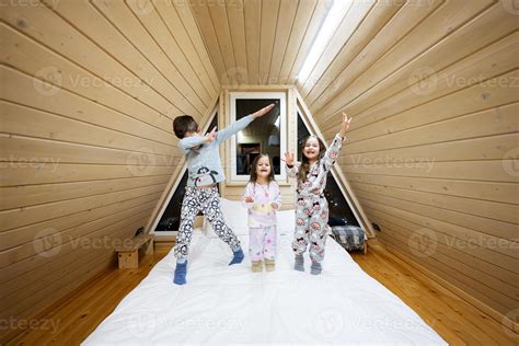 Children in soft warm pajamas playing at wooden cabin home. Concept of