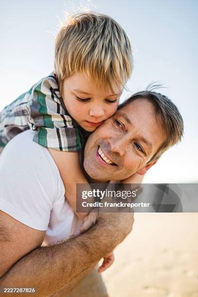 father carrying son  shoulders  beach stock  high res