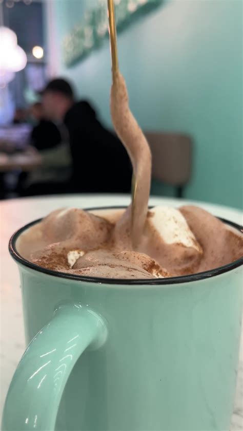 stir with a golden spoon delicious hot chocolate with marshmallows