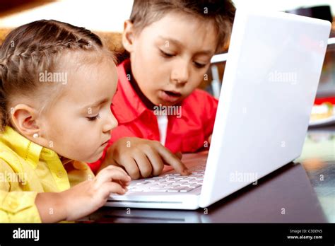 Portrait of cute children typing on laptop Stock Photo - Alamy