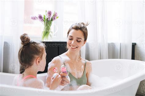 Young mother woman and little tween girl daughter having fun in bath