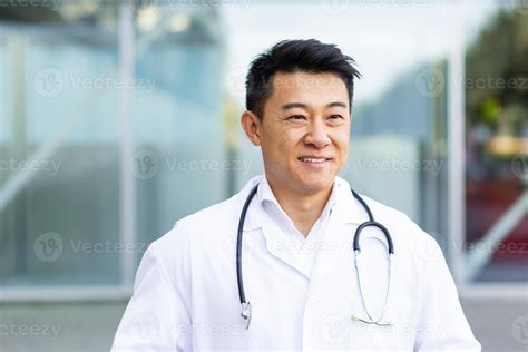 portrait of a cheerful asian doctor man smiling on the background of a