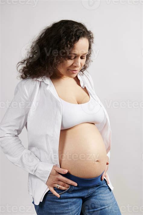 Beautiful curly haired multi ethnic pregnant woman with naked belly