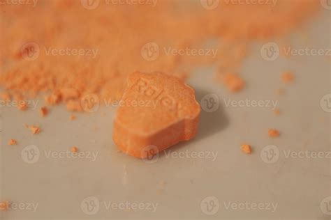 Orange pills with mdma ecstasy dope rolex drug close up background fine