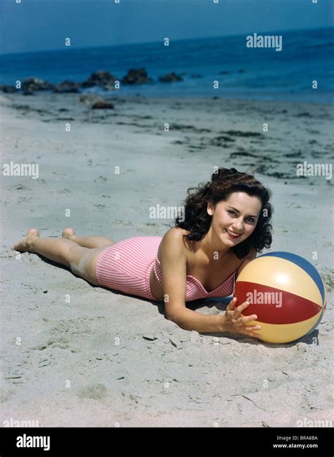 1940s 1950s BRUNETTE WOMAN LYING ON BEACH HOLDING BEACH BALL Stock ...