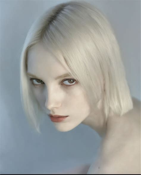 Blond woman with blue eyes and a white dress posing for a picture