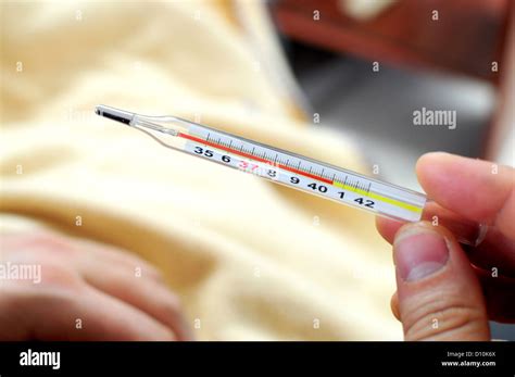 Hand holding thermometer showing high temperature Stock Photo - Alamy