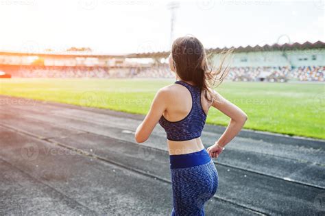Portrait of a strong fit girl in sportswear running in the stadium