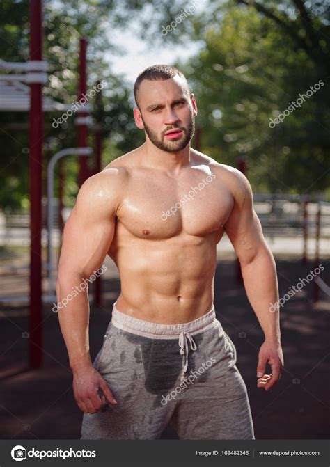 Sexy and muscular shirtless bodybuilder man showing off on a blurred