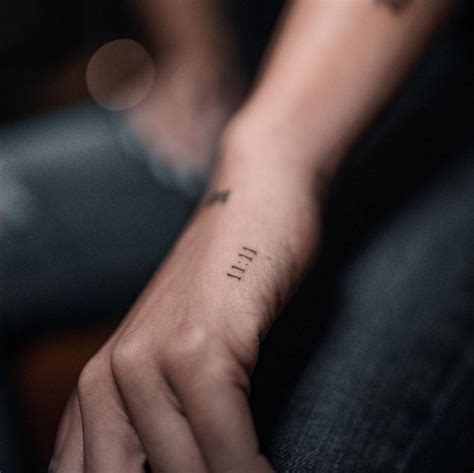 "11:11" lettering tattoo on the hand.