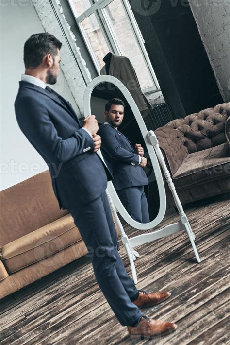 Elegant look. Full length of handsome young man in full suit adjusting