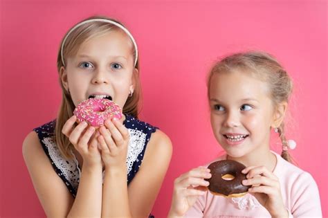 Comendo As Duas Irmã - Duas irmãs loiras em vestidos coloridos eles estão comendo rosquinhas ...
