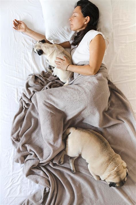 Mujer durmiendo en la cama con sus dos perros pug | Foto Premium