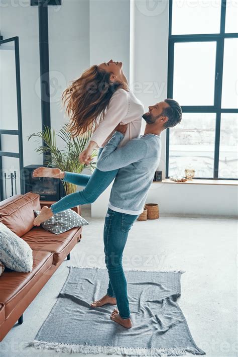 Full length of young playful couple smiling and dancing while bonding