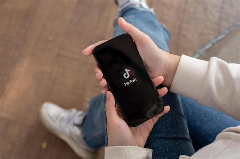 A close-up shot of a woman using the TikTok application on her iPhone