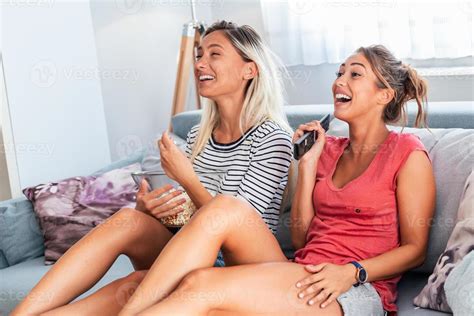 Girlfriend watching a very funny movie and eat popcorn. Smiling young ...