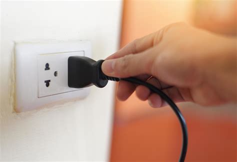 plug  wall  hand  black power cord cable unplug  plugged