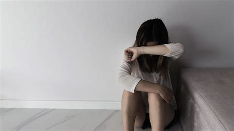 Young person woman sad, stress and loneliness sitting in dark room