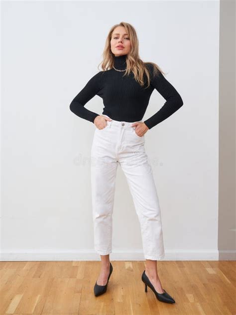 elegant female model poses  stylish black top  white pants