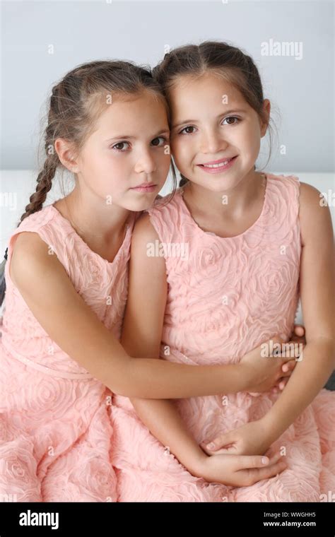 Portrait of cute twin girls on light background Stock Photo - Alamy