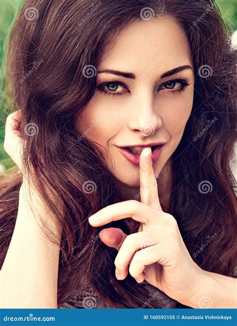 Brunette Woman with Bright Green Eyes Showing Secret Sign Holding