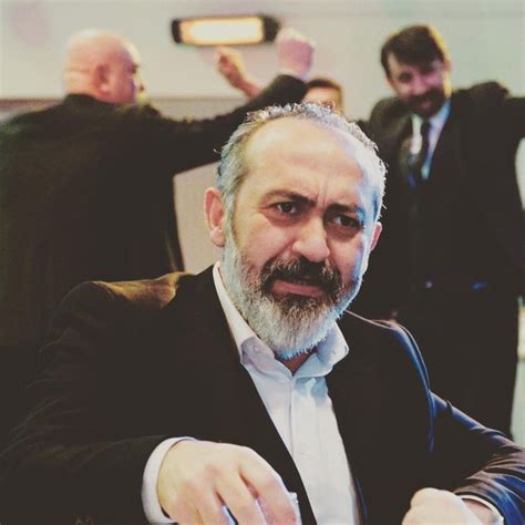 a man in a suit and tie sitting at a table with his hands up to the side