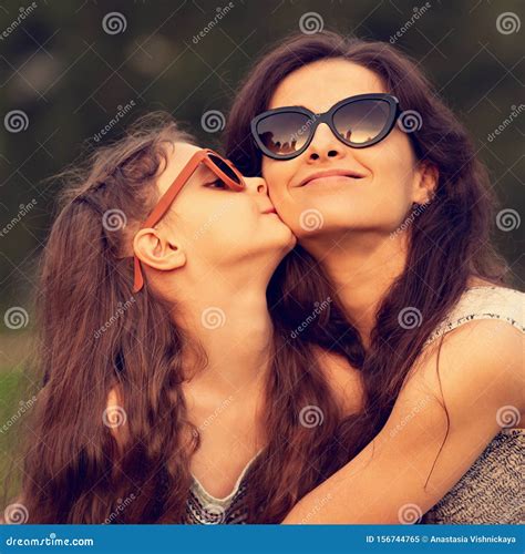 Happy Fashion Daughter Kissing and Embracing Her Mother in Trendy