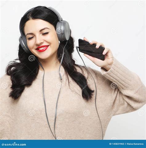 Νέα Curvy γυναίκα Brunette στα ακουστικά που ακούει τη μουσική Στοκ