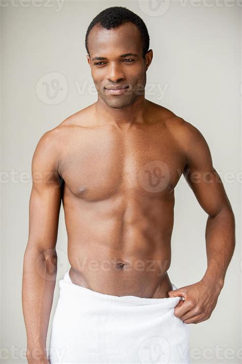 Real macho. Young shirtless African man wrapped in towel looking away