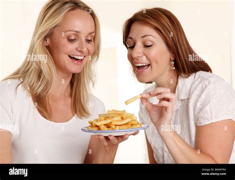 TWO WOMEN EATING FRENCH FRIES Stock Photo - Alamy