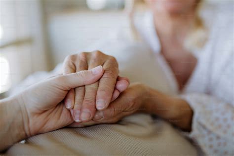A close up caring grown up daughter holds mother hand provides