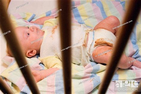 Neglected baby lying in dirty cot wearing soiled nappy, Stock Photo ...