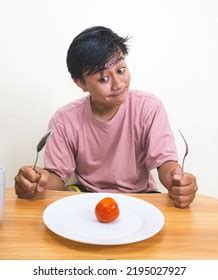 sad hungry man eating vegetables isolated stock photo