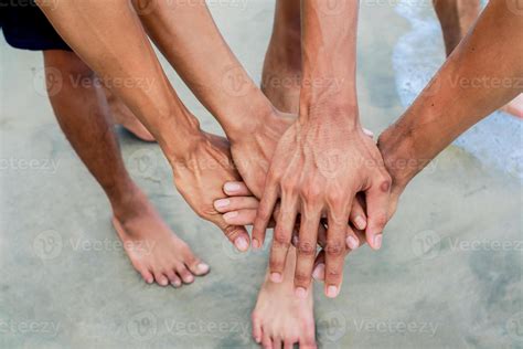 unido manos en arenoso playa simbolizando grupo cohesión y colaboración