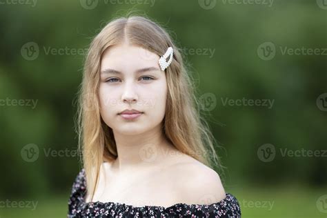 Portrait of a beautiful girl with long hair on a summer background. The