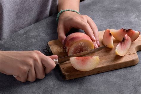 authentic female hands cutting  fresh ripe peach  wooden cutting