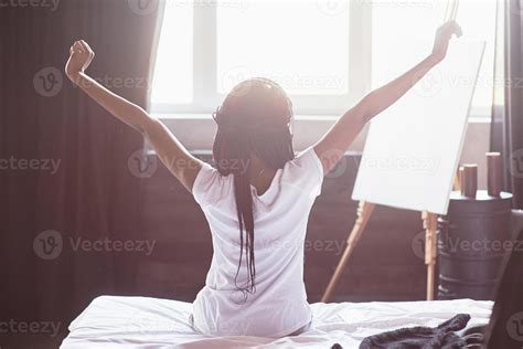 Beautiful black woman waking up in her bed, she is smiling and