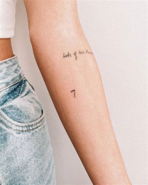 Minimalist number "7" tattoo on the inner forearm.