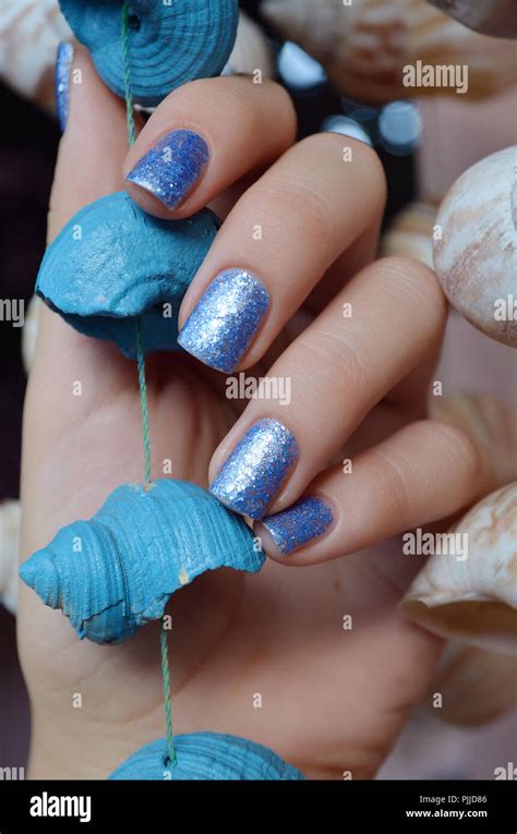 Female hands with blue glitter nail design holding sea shell Stock ...