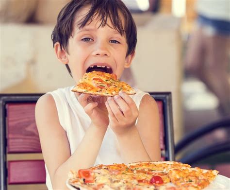 The boy is eating pizza stock photo. Image of adorable - 99245308