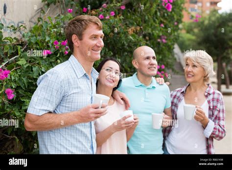 mature cheerful males  females drinking coffee outdoors stock photo