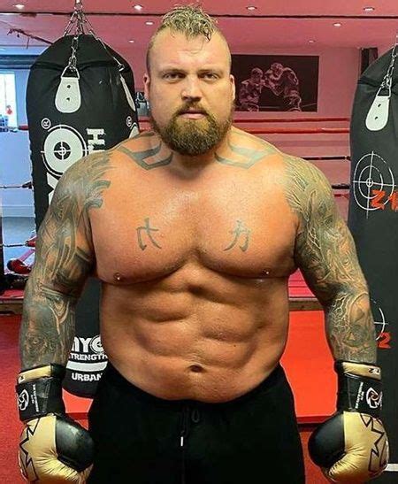 a man with tattoos and boxing gloves standing in front of two punching ...