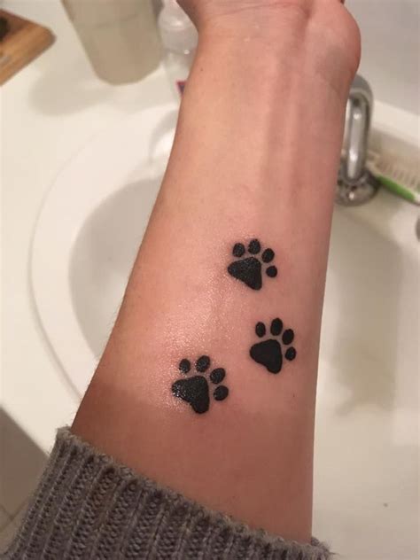 a person's arm with paw prints on it and a sink in the background